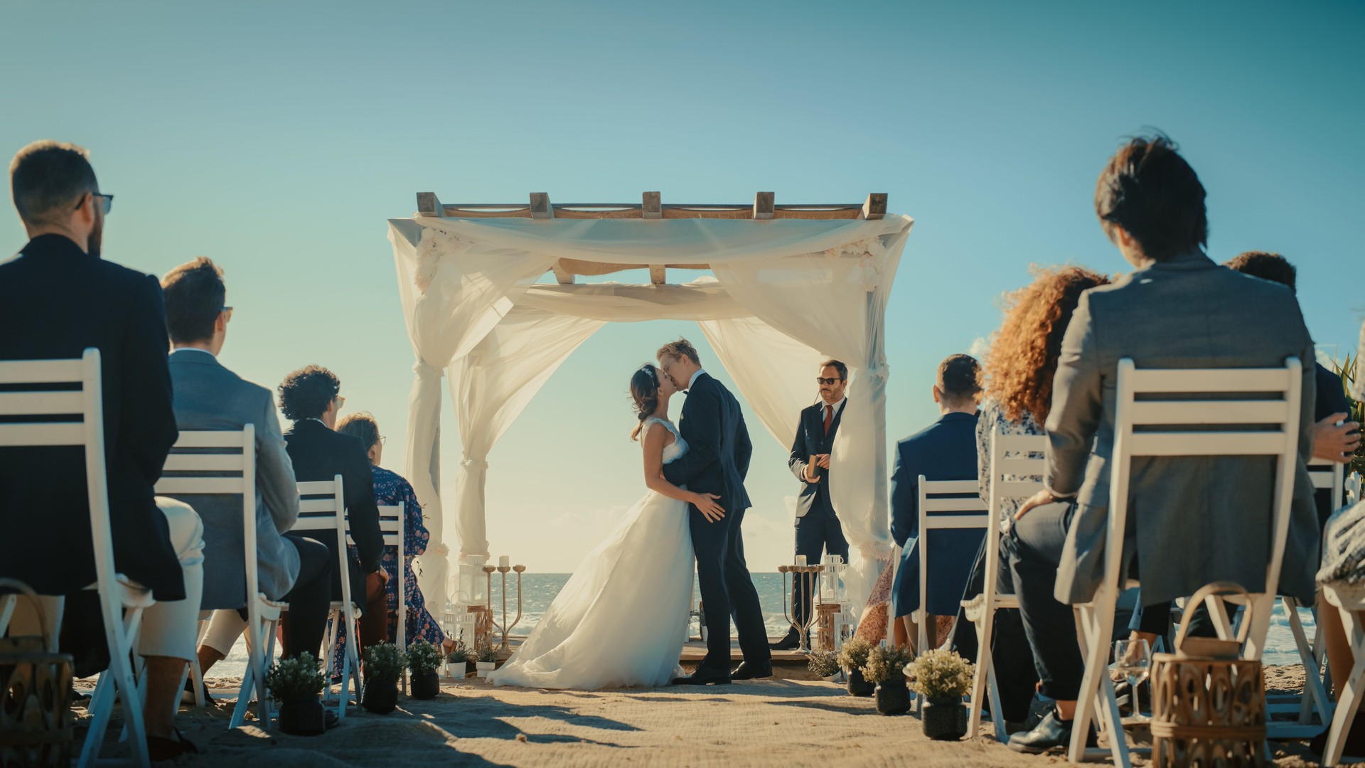 Beautiful Bride and Groom During an Outdoors Wedding Ceremony on an Ocean Beach. Perfect Venue for Romantic Couple to Get Married, Exchange Rings, Kiss and Share Celebrations with Multiethnic Friends.